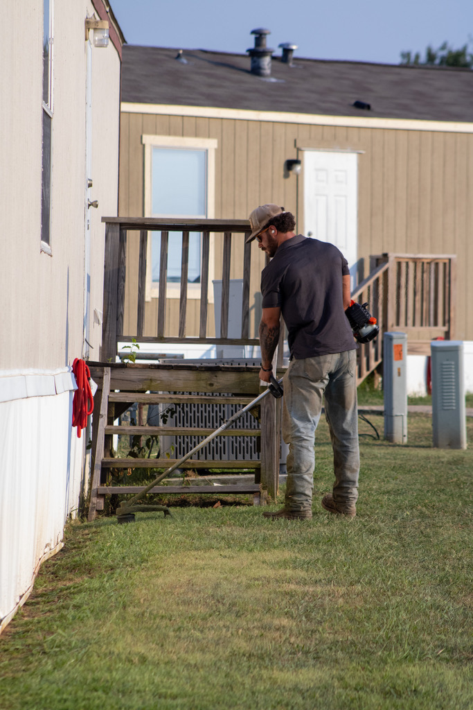 Crew member trimming along a home